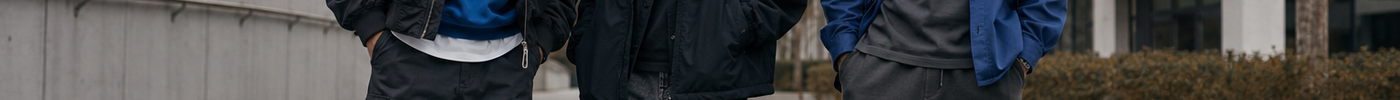 Three people wearing cobalt and charcoal layered streetwear in an autumn city