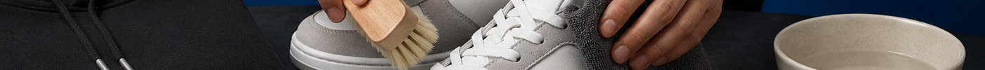 Cleaning unbranded sneakers beside a folded hoodie and shoe-care tools