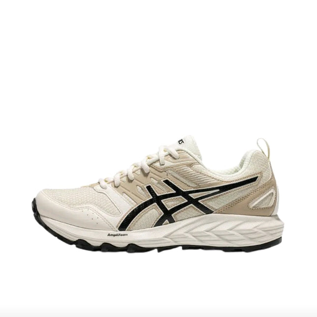 Beige and white athletic shoe with black logo, textured sole, and lace-up design.