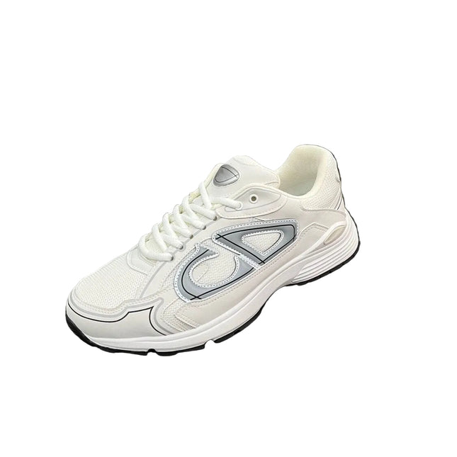 A white athletic sneaker with a large silver and gray side logo, displayed on a black textured suitcase against a background of silver curtains.