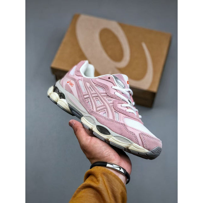 Pink sneaker held in a hand with a brown box in the background