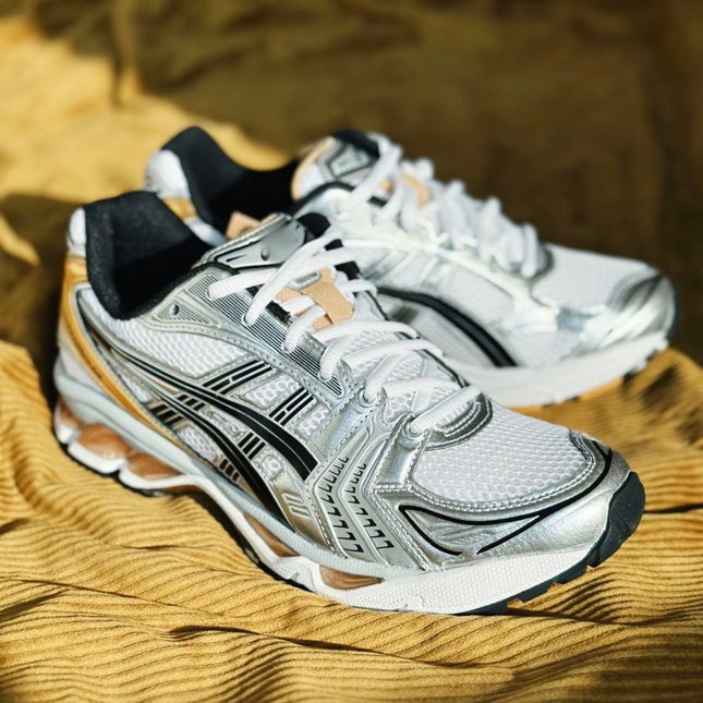 White and silver athletic shoes with black accents on a textured yellow fabric background.