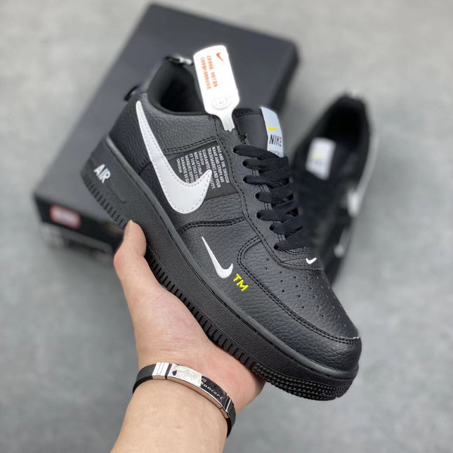 Black sneaker with white accents held by a hand on a gray background