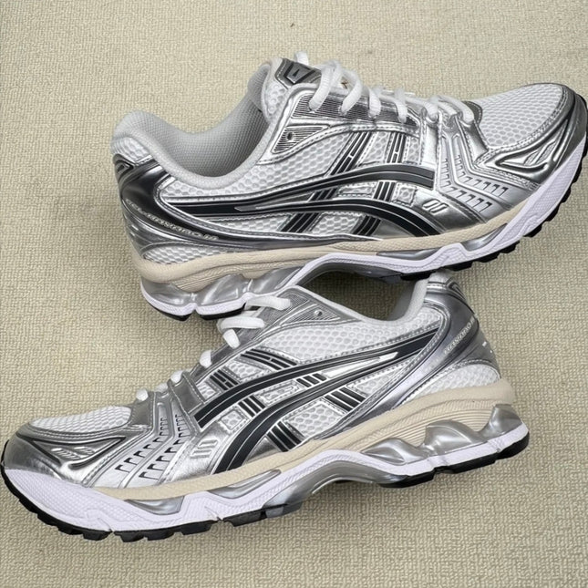 White and silver sneakers with black stripes and textured mesh on a light gray carpet.