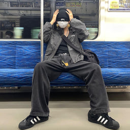 Streetwear outfit wearing black adidas Superstar II sneakers on a subway